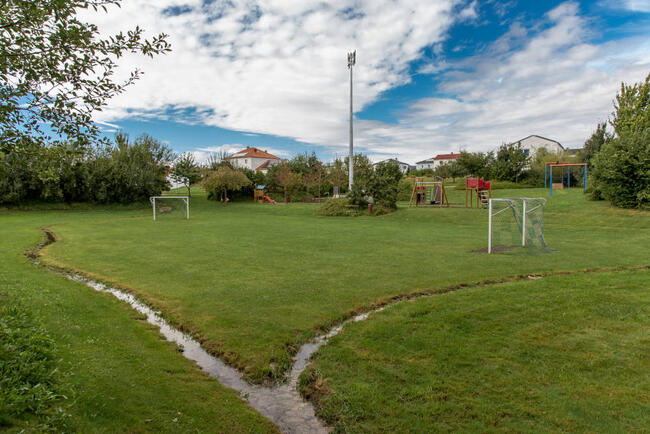 Integration eines Regenrückhaltebeckens in eine Grün- und Spielplatzfläche.