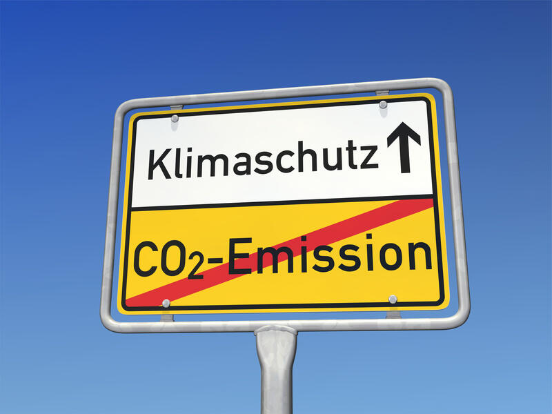 Ortsschild mit Text "Klimaschutz". Außerdem mit durchgestrichenem Text "CO2-Emissionen".